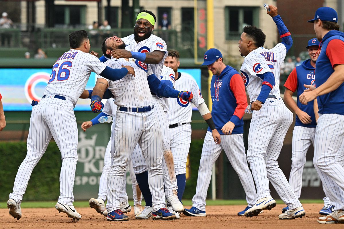 Rafael Ortega #66 of the Chicago Cubs and Franmil Reyes #32 surround Willson Contreras #40 and celebrate after a Contreras walk-off single gave Chicago the 6-5 win over the Milwaukee Brewers in 11 innings at Wrigley Field on August 20, 2022 in Chicago, Illinois.