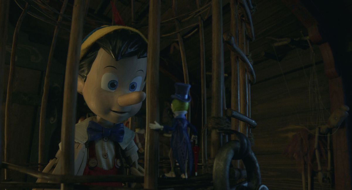 A weirdly dead-eyed CG Pinocchio stares at Jiminy Cricket from a cage in Disney’s live-action remake of 1940’s animated classic Pinocchio