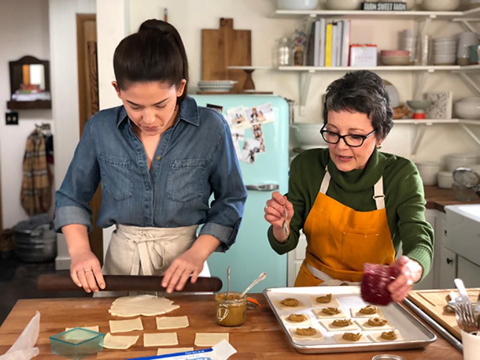 Molly Yeh rolls out pastry dough while her mother-in-law, Roxanne Hagen, places pistachio butter on her Pocket Pastries with Raspberry Jam.