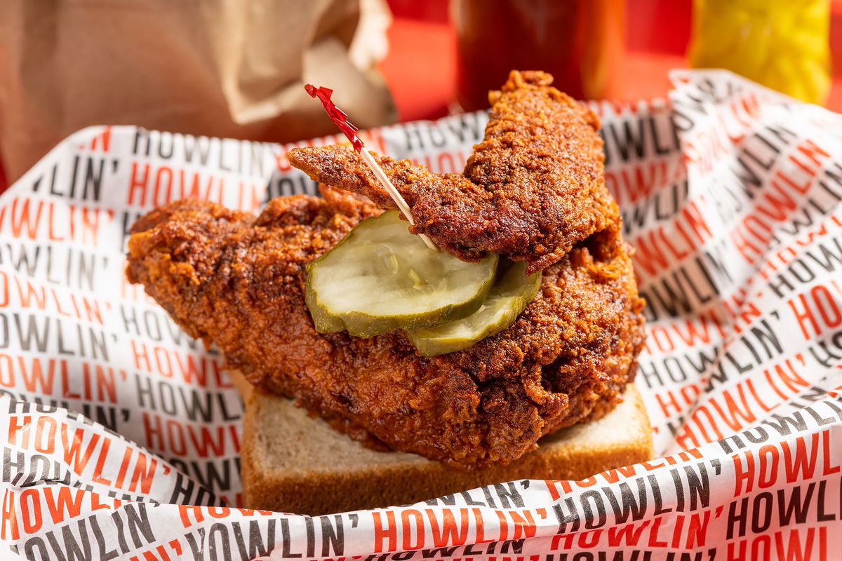 A close-up shot of hot chicken on with pickles on a piece of white bread at Howlin’ Ray’s.