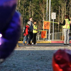 With a memorial in the foreground, people walk to school at Emma L. Carson Elementary School in Puyallup, Wash., Monday, Feb. 6, 2012.