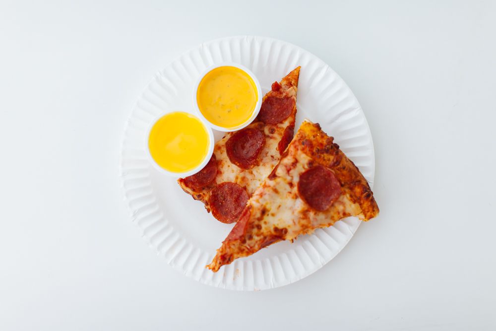 Two pizza slices with two bright-yellow sauces.