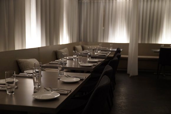 The dining room at Dessous features low lighting and white ethereal curtains.