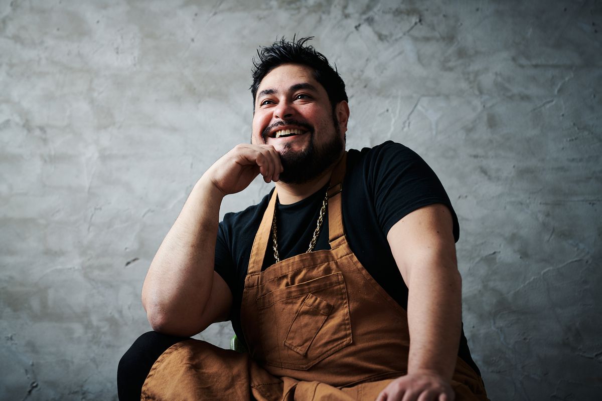 A man in a chef’s apron, laughing.