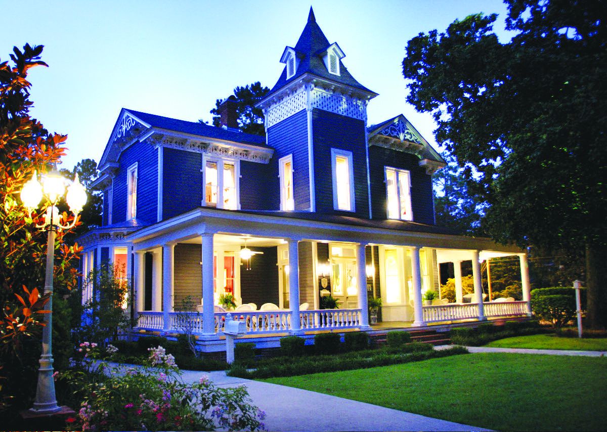 Blue Victorian house lit up at night.