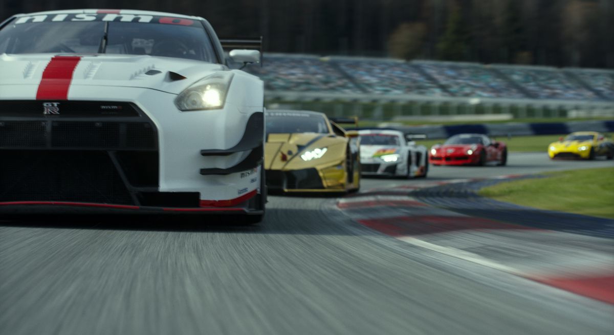 A dynamic low shot of a racing cars at speed, led by a white Nissan, in the Gran Turismo movie