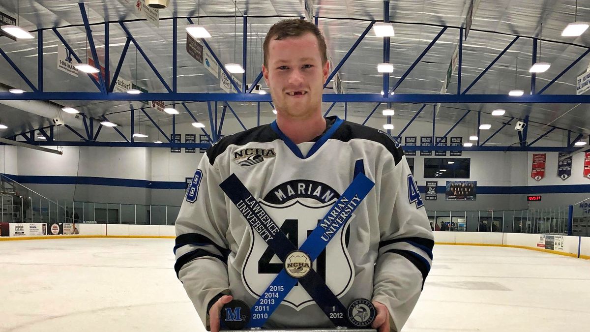 College hockey player Brock Weston holds a trophy.