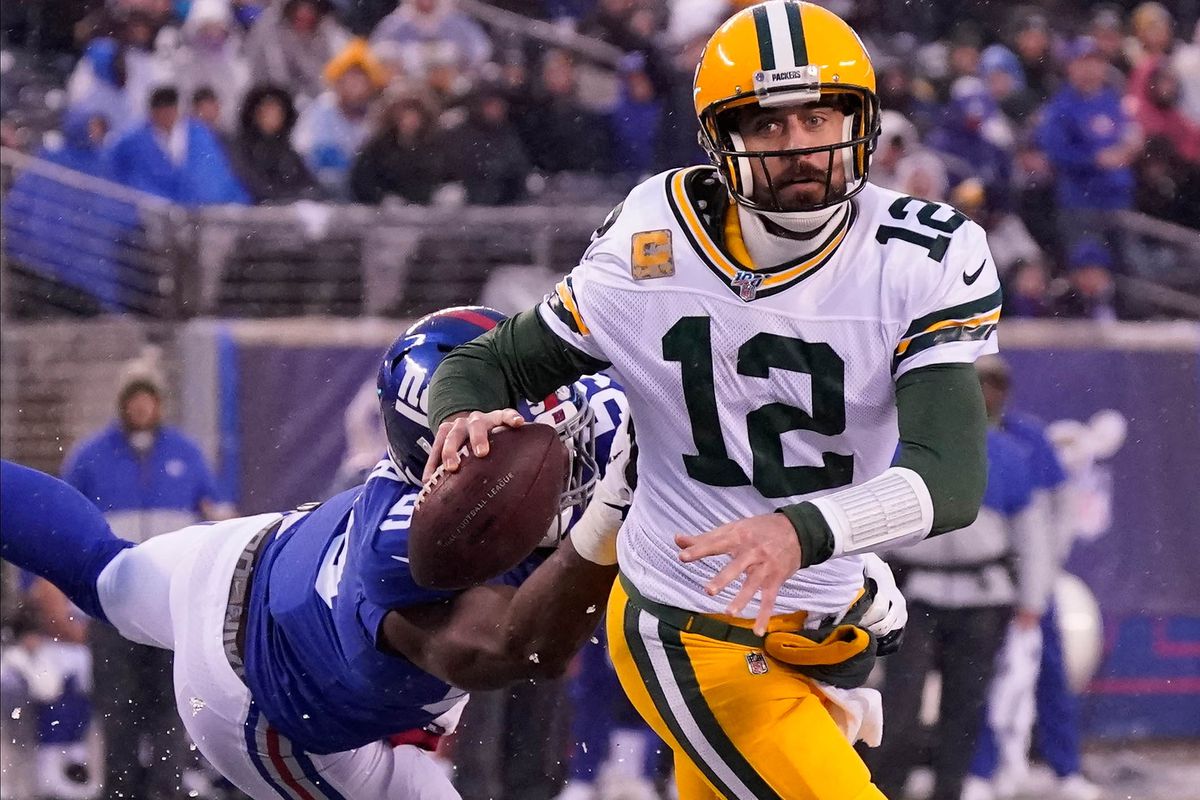 Green Bay Packers quarterback Aaron Rodgers breaks free from the grasp of New York Giants linebacker Lorenzo Carter to throw a fourth quarter TD pass at MetLife Stadium.