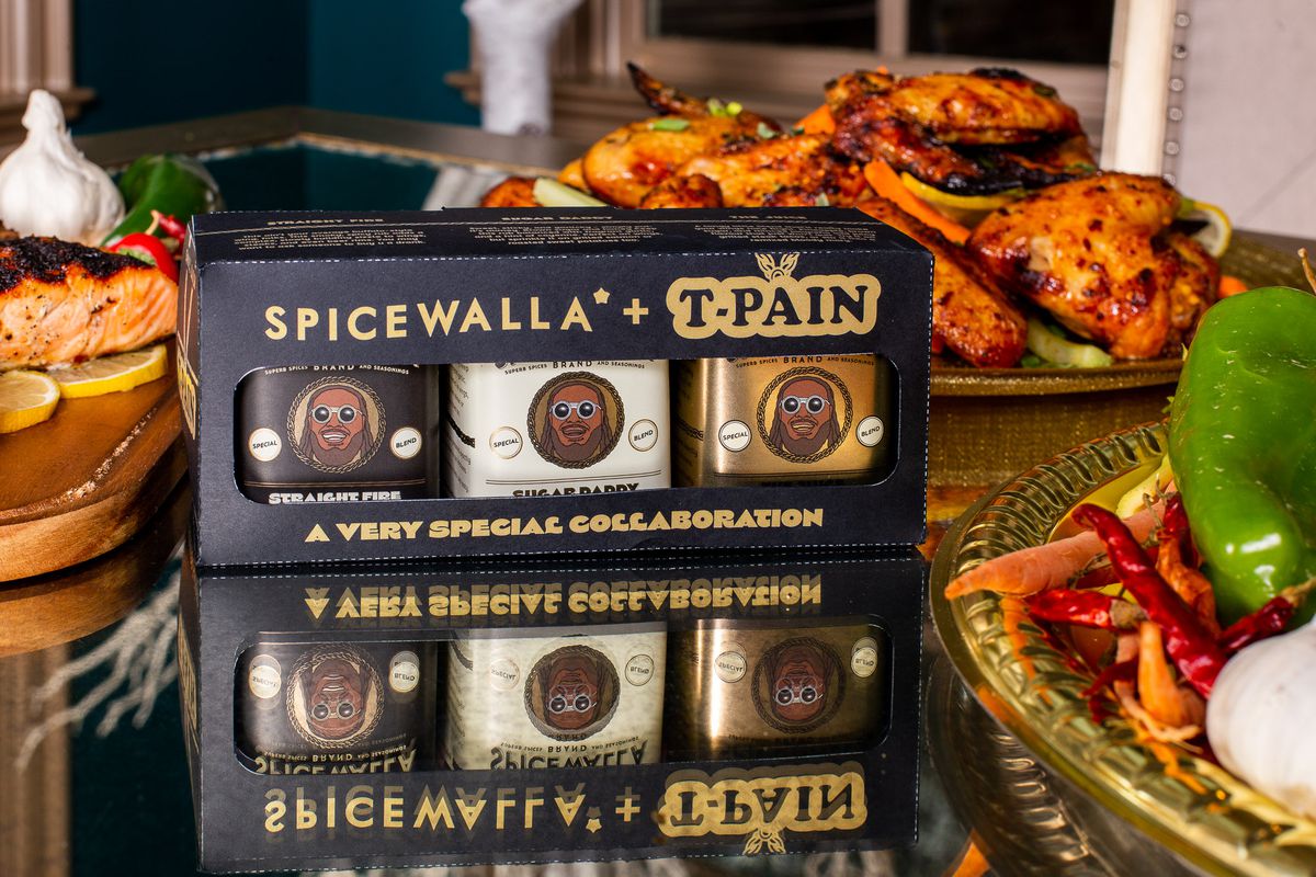A set of three spice tins in front of plates of chicken wings. 