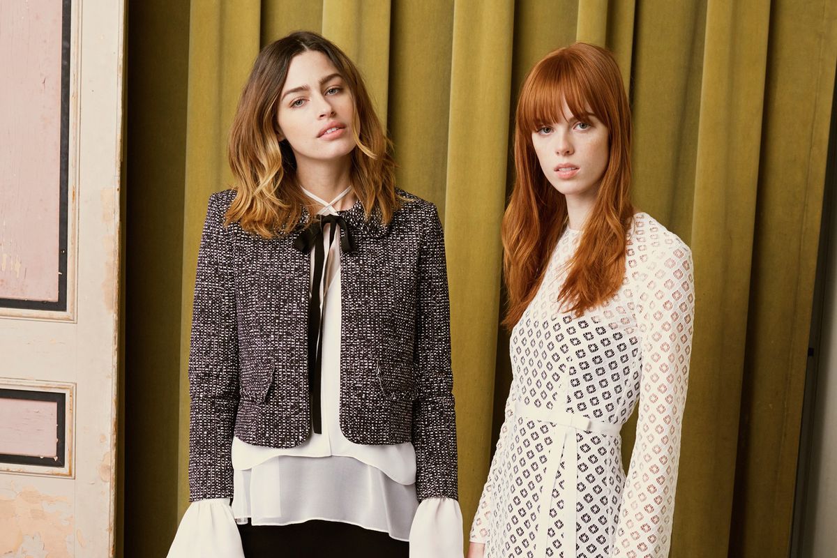 Two models wearing Cinq á Sept clothing, standing in front of a doorway