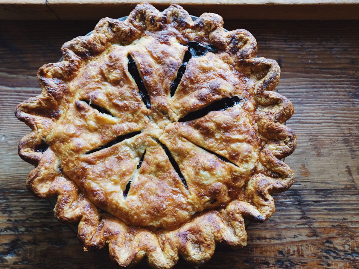 A double-crusted blueberry pie from Lauretta Jean’s sits on a wooden countertop.