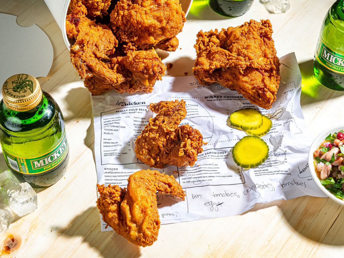 Pieces of fried chicken, beers, and pickles scattered over a menu.