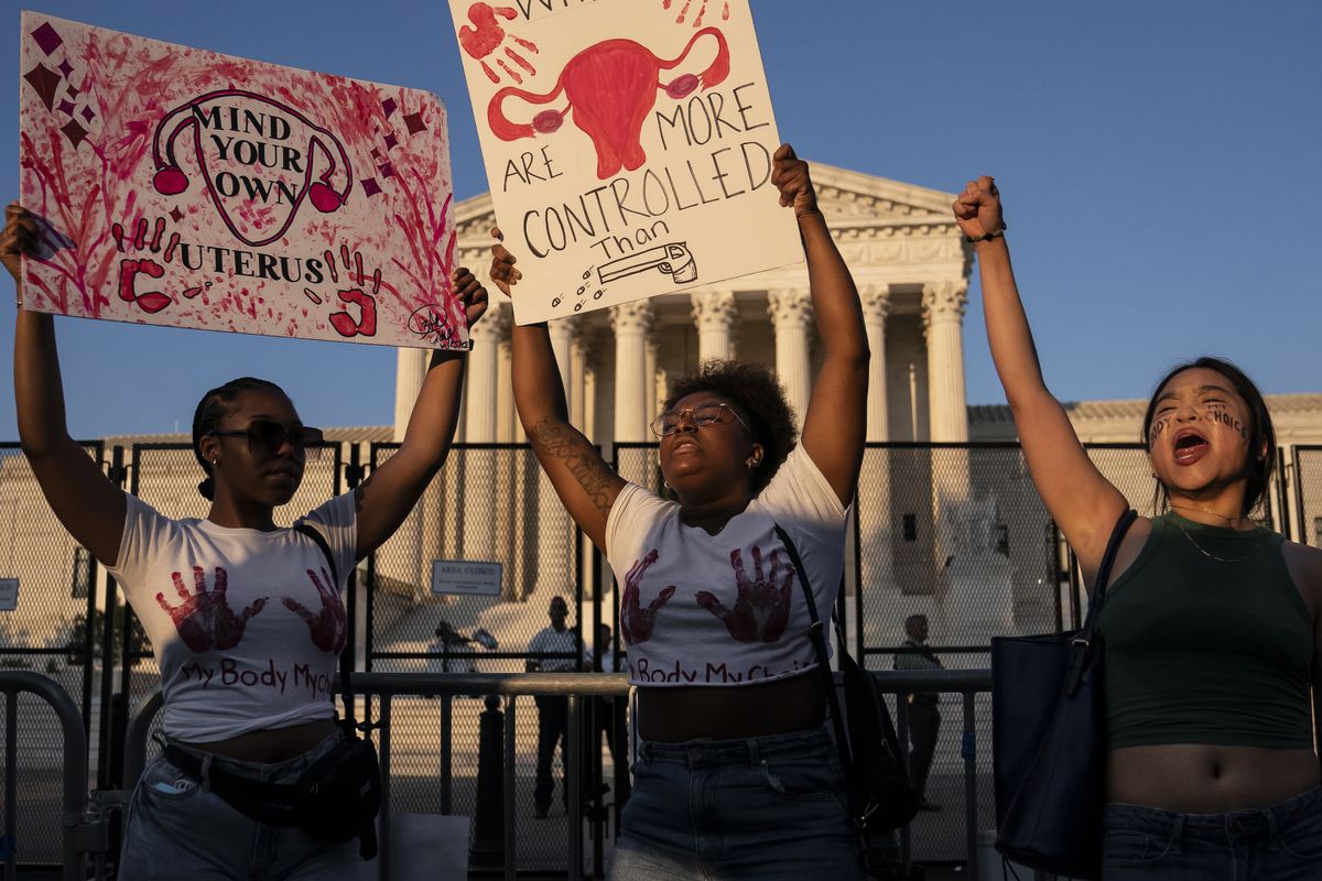 Aktivis hak aborsi berkumpul di depan Mahkamah Agung menyusul pengumuman keputusan Dobbs v. Jackson Women's Health.  Satu orang memegang tanda yang berbunyi, 