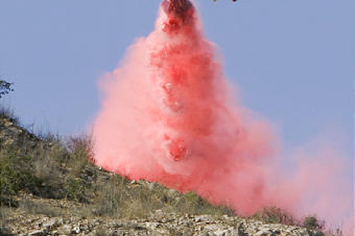 An air tanker drops fire retardant near homes where a wildfire driven by powerful Santa Ana winds threatened homes, Monday in Malibu, Calif.