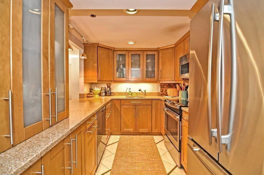 A kitchen with a U-shaped counter and a. there are large cabinets and a double-door fridge. 