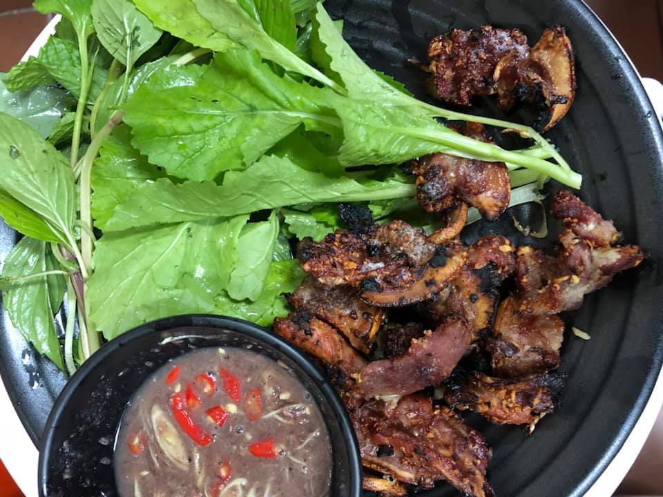 A dish of grilled boar with a spicy dipping sauce and greens