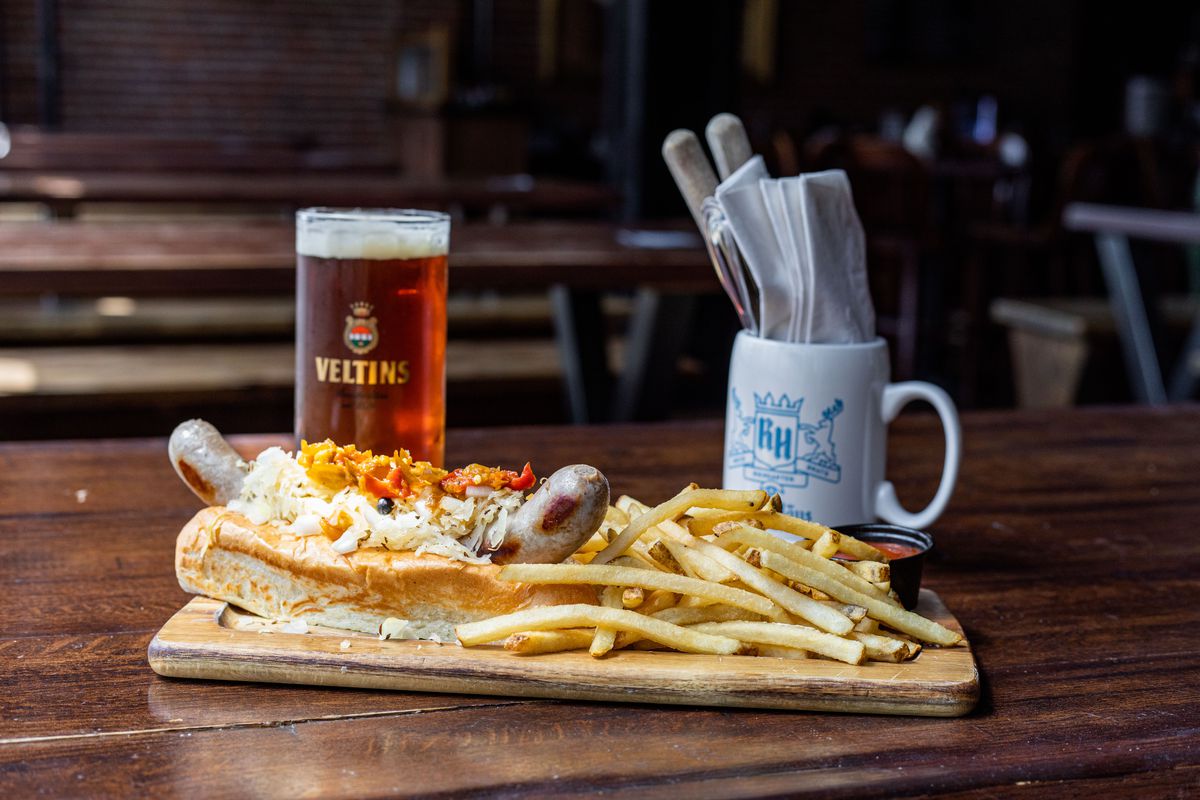 Brat on a bun with fries and a beer