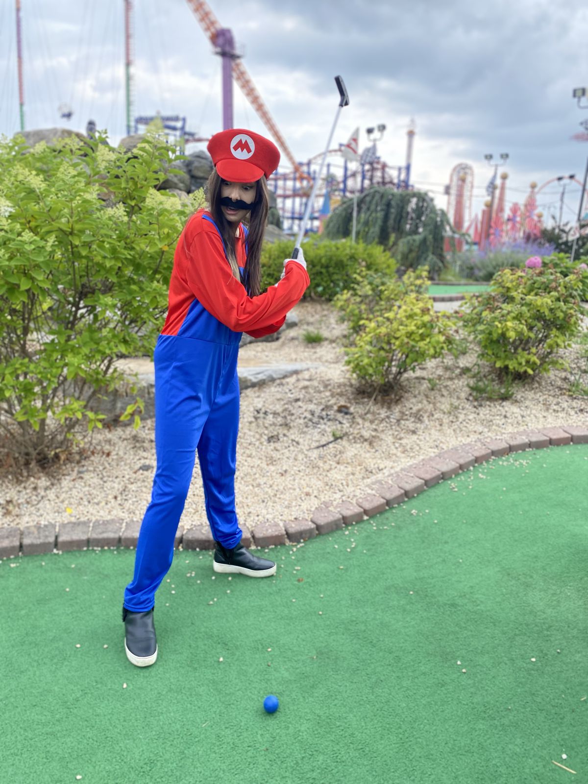 XTina GG takes a swing at a mini golf course while dressed as Mario