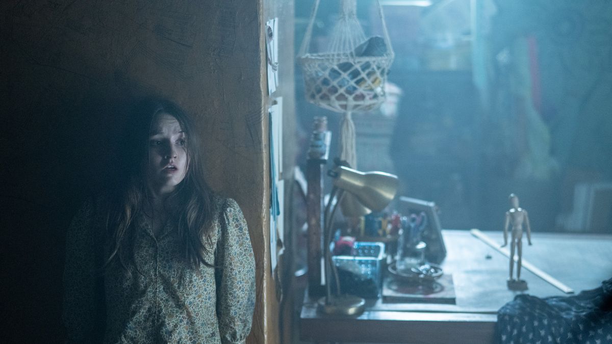 Kaitlyn Dever as Brynn Adams hides from a wooden joint doll in No One Will Save You