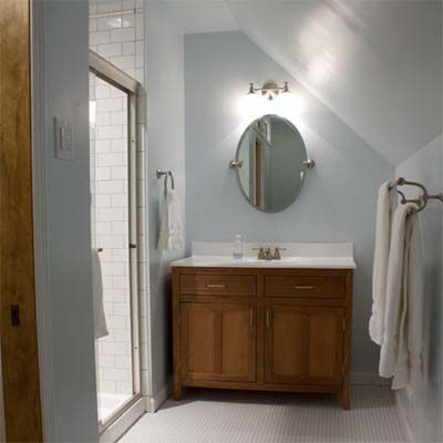 Bathroom with light and oval mirror above sink.