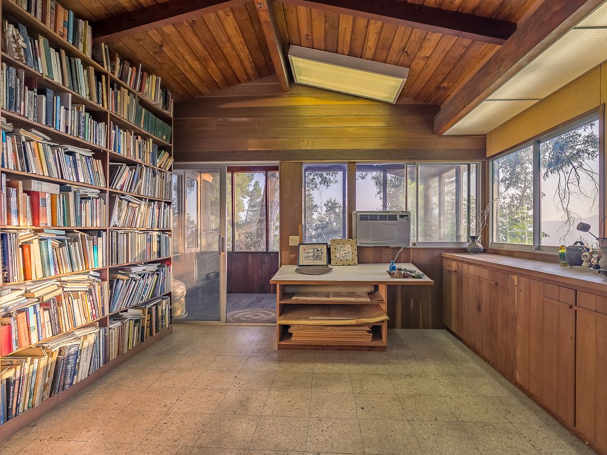 A room with floor-to-ceilings bookshelves, and wrap-around windows. 
