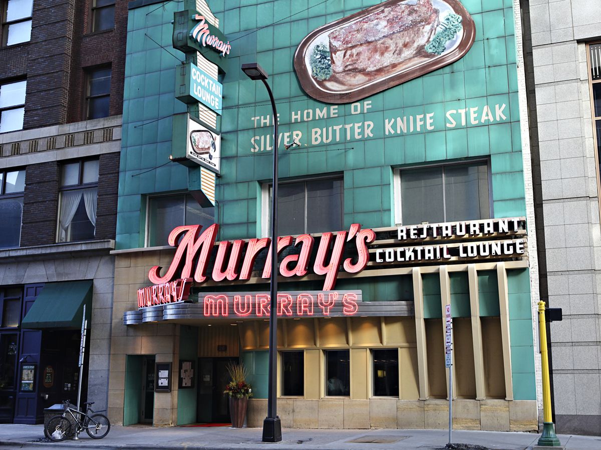 Murray’s Steakhouse exterior with a red neon sign and teal exterior with a hand-painted steak decal.