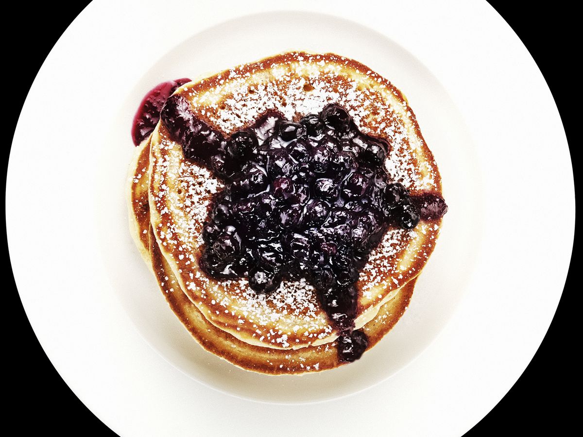 An overhead photograph of a plate of pancakes with blueberries.
