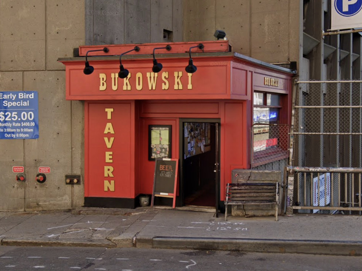 A red-painted exterior of a bar with “Bukowski Tavern” in large letters running over the top and down the side of the building.