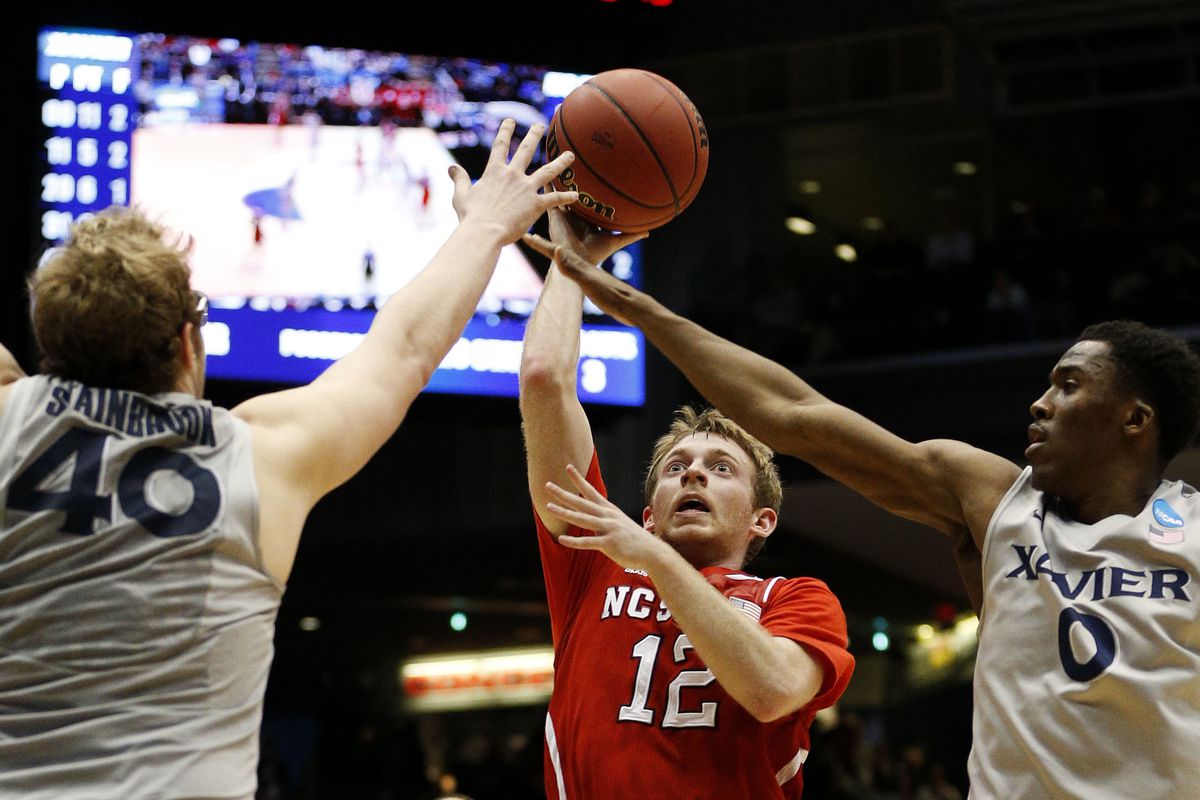 DAYTON, OH - MARCH 18: Tyler Lewis #12 of the North Carolina State Wolfpack goes up between Matt Stainbrook #40 and Semaj Christon #0 of the Xavier Musketeers in the second half during the first round of the 2014 NCAA Men's Basketball Tournament at a