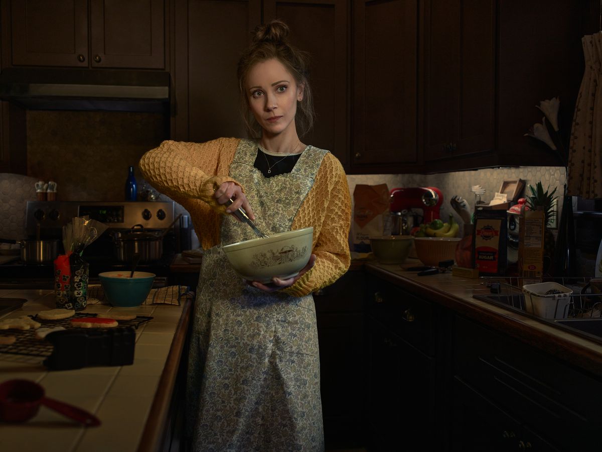 Juno Temple as Dot Lyon stands in an apron with a mixing bowl in her hands in Fargo season 5