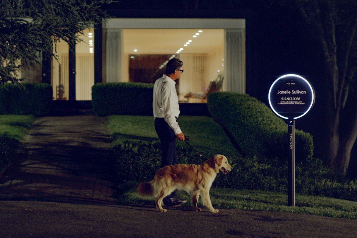 Man and dog walking in front of glowing for sale sign