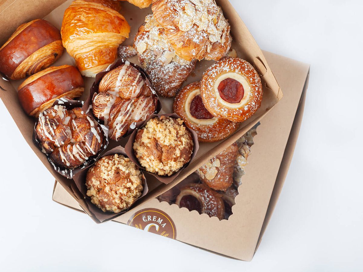 An overhead tan box of pastries, open at the lid.