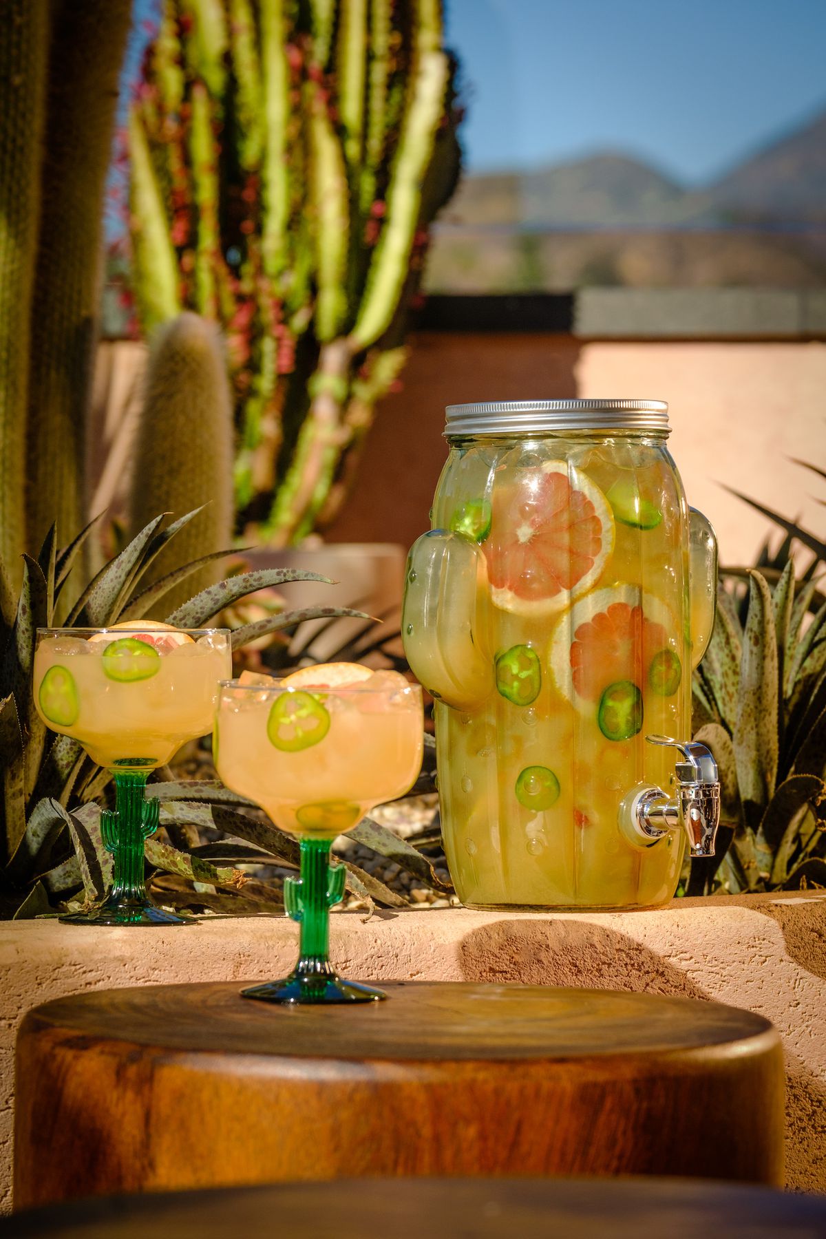 A cactus-shaped vessel holding multiple cocktails while margarita glasses sit beside.