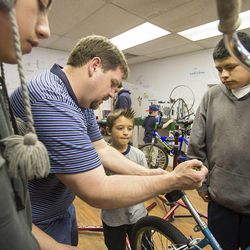 Mike Robinson lends a hand to Tyson Schaaf, Aiden Connole and Ruben Aguilar as kids involved in Peer Court work on bikes at the Salt Lake City Bicycle Collective Wednesday, March 12, 2014.