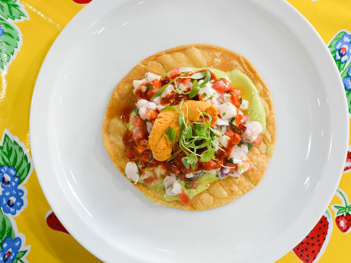 Colorful uni-topped ceviche tostada on a white plate with colorful tablecloth at Holbox.