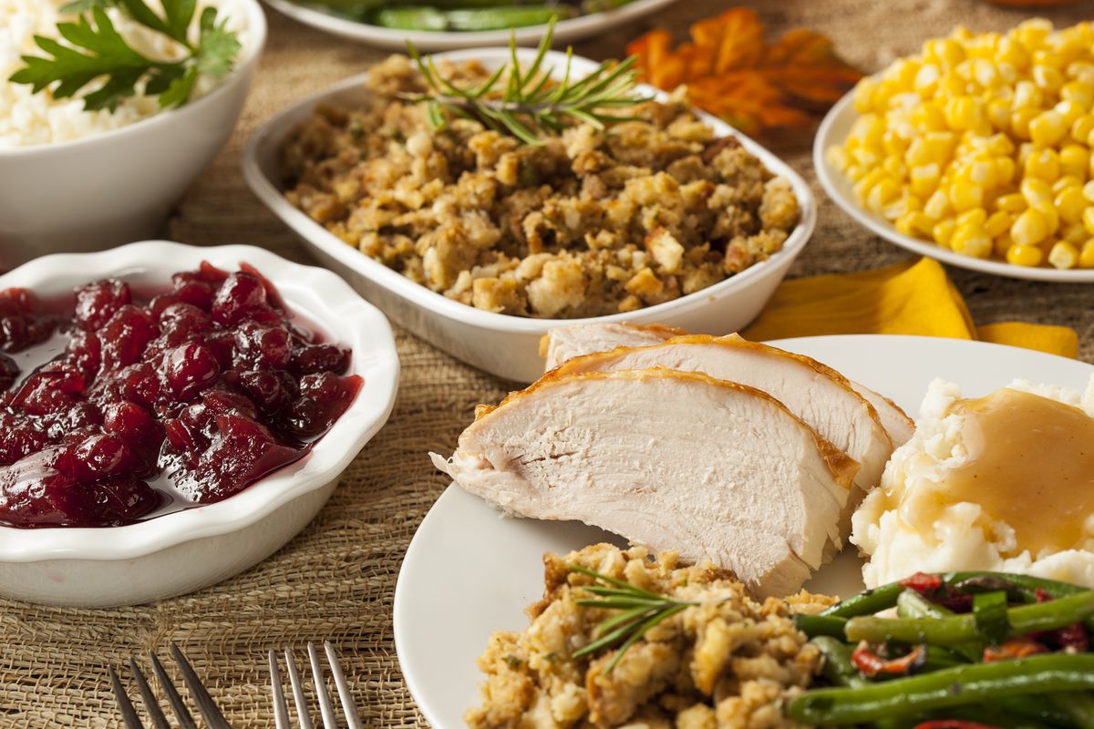 A table with turkey, stuffing, cranberry sauce, and corn