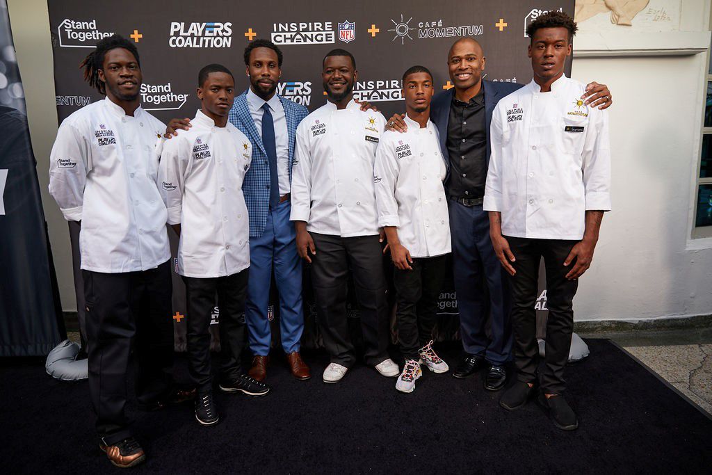 A group of men pose in front of a Stand Together screen at an event during the 2019 Super Bowl 