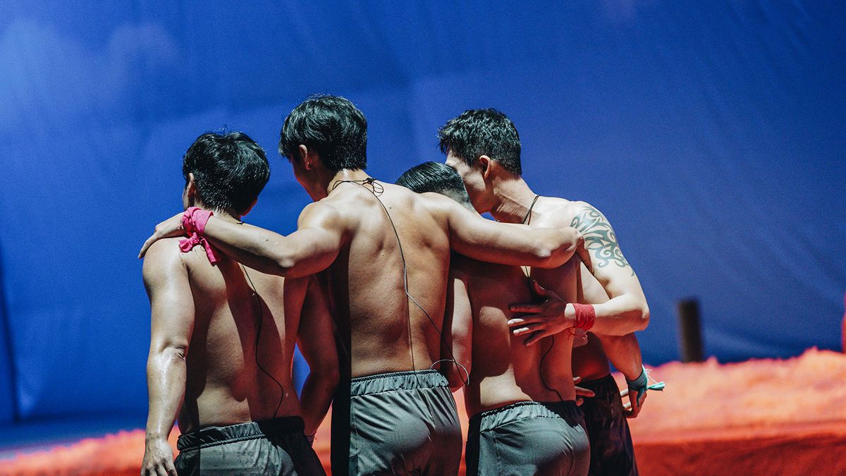 A group of contestants walking away with their arms around each other in a still from Physical 100