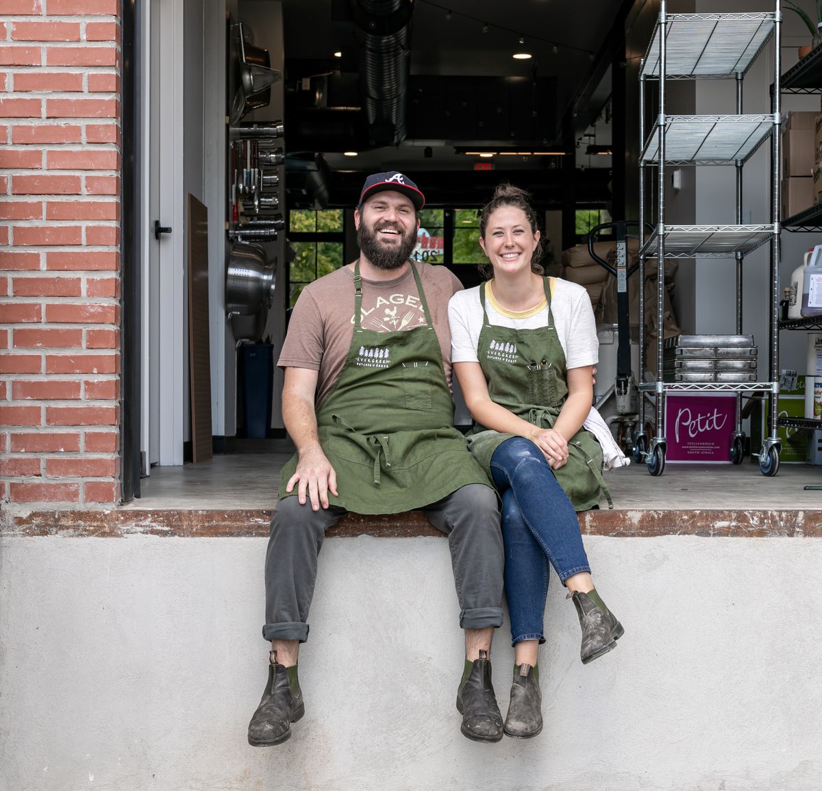 Sean Schacke and Emma Schacke sitting on the loading dock of their Kirkwood bakery and butchery