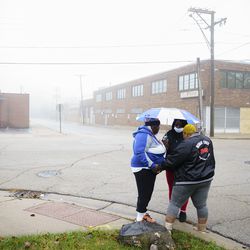 Three woman pray at the intersection where Marcellis Stinnettte was fatality shot by police in Waukegan, Thursday, Oct. 22, 2020.