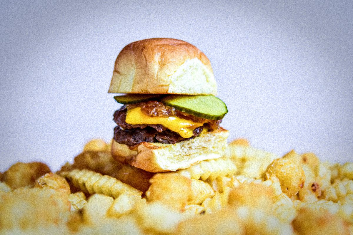 A slider on top of a pile of crinkle fries.