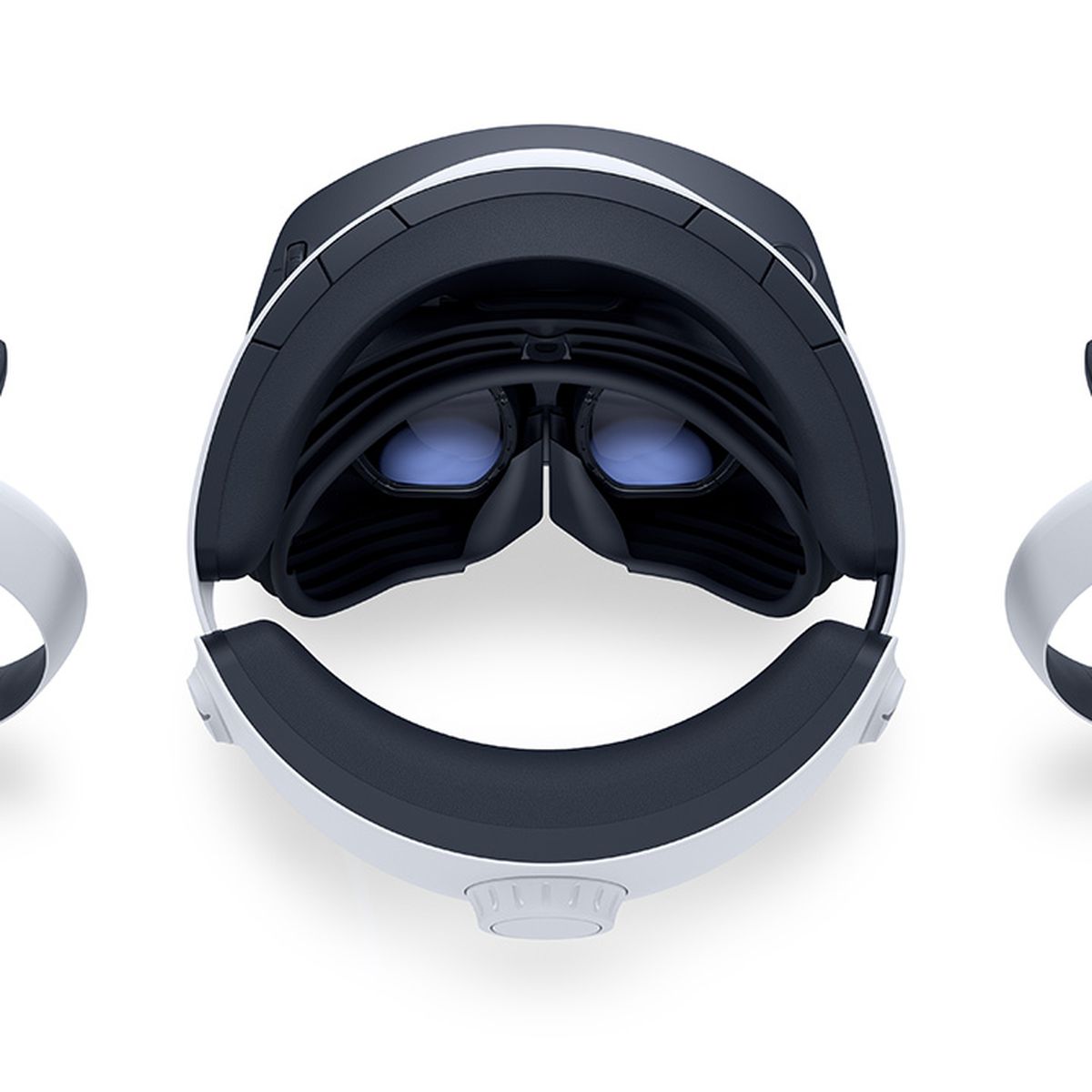 The PSVR 2 headset, as seen from above, resting on a white surface, flanked by both VR2 Sense controllers