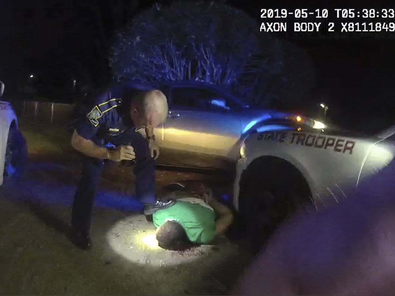 This image from video from Louisiana state police state trooper Dakota DeMoss’ body-worn camera, shows trooper Kory York bending over with his foot on Ronald Greene’s shoulder after he was taken into custody on May 10, 2019, outside of Monroe, La. 