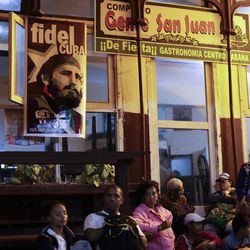 People sit outside a restaurant as they wait for the motorcade transporting the remains of Cuban leader Fidel Castro in Havana, Cuba, early Wednesday morning, Nov. 30, 2016. Castro's ashes have begun a four-day journey across Cuba from Havana to their final resting place in the eastern city of Santiago. 
