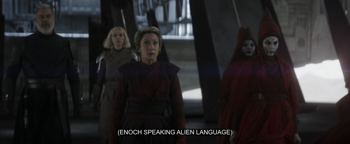 Ahsoka’s bad guys, lead by Morgan Elsbeth, with a subtitle on the screen that reads “(ENOCH SPEAKING ALIEN LANGUAGE)”. 