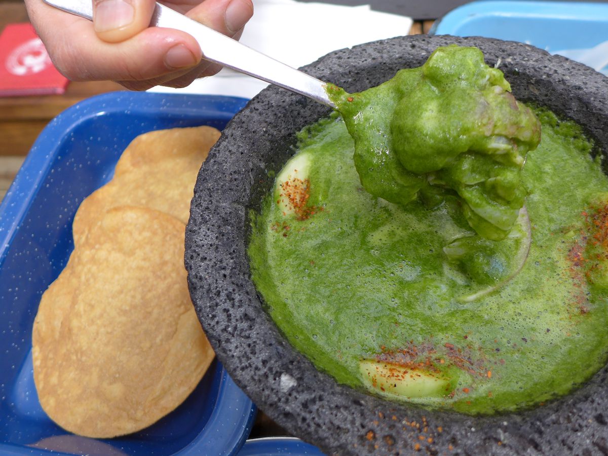 Molcajete filled with green liquid and shrimp.