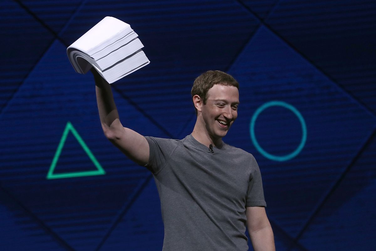 Facebook CEO Mark Zuckerberg onstage holding a large pile of papers over his head
