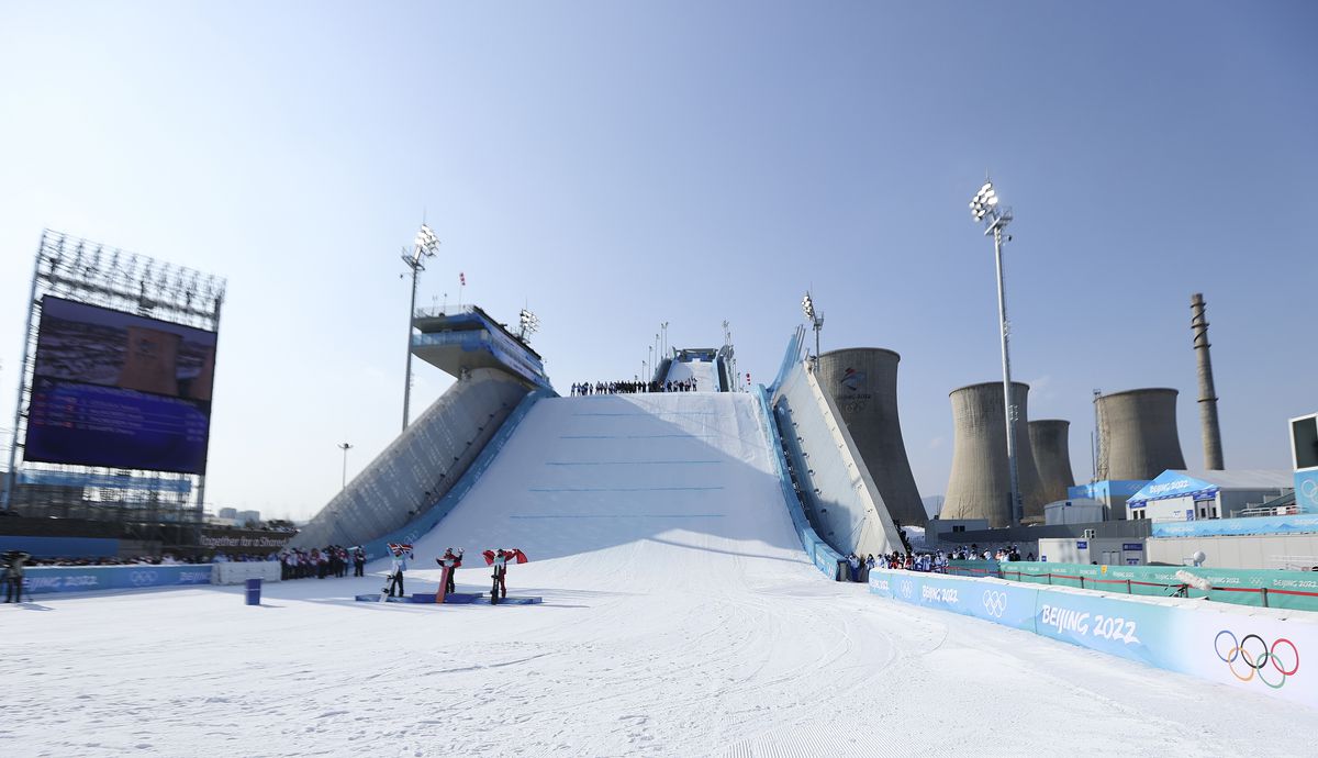 A snowboard slope is next to the towers of a former steel mill.