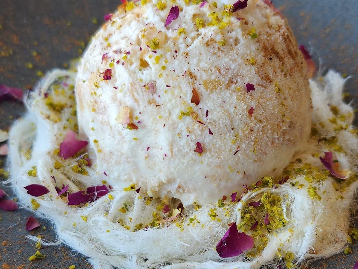 Ice cream topped with rose and pistachio.