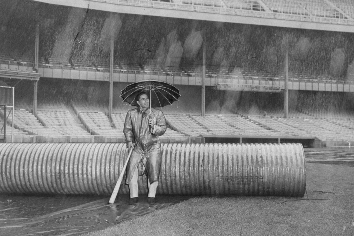 Yankees’ shortstop Phil Rizzuto sits under umbrella in the r